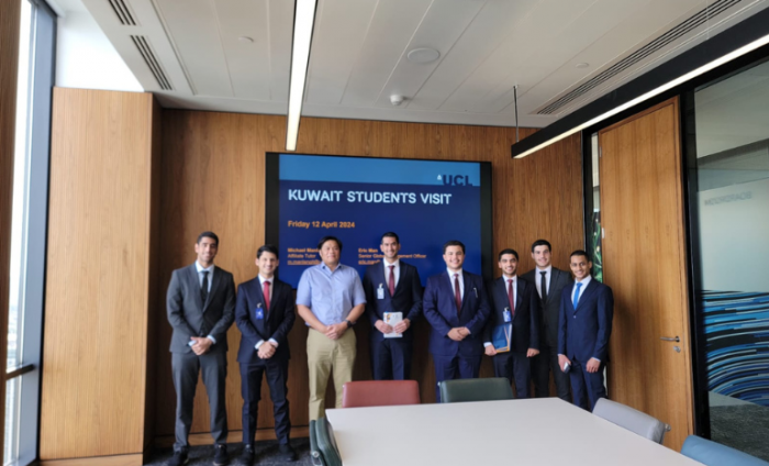 A group photo of an academic professor and university students in a boardroom.