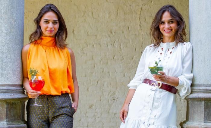 Photo of two female Double Dutch founders standing against two columns holding a glass of their tonic mixers